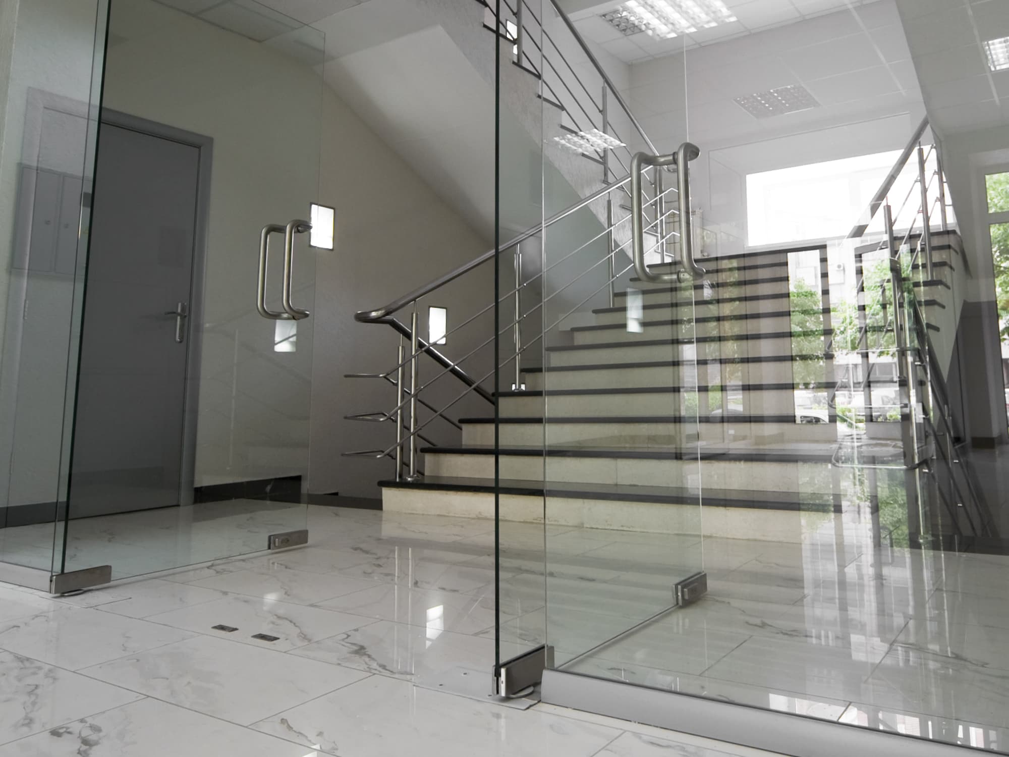 Treppenhaus mit Glasgelaender und Stufen in Marmoroptik