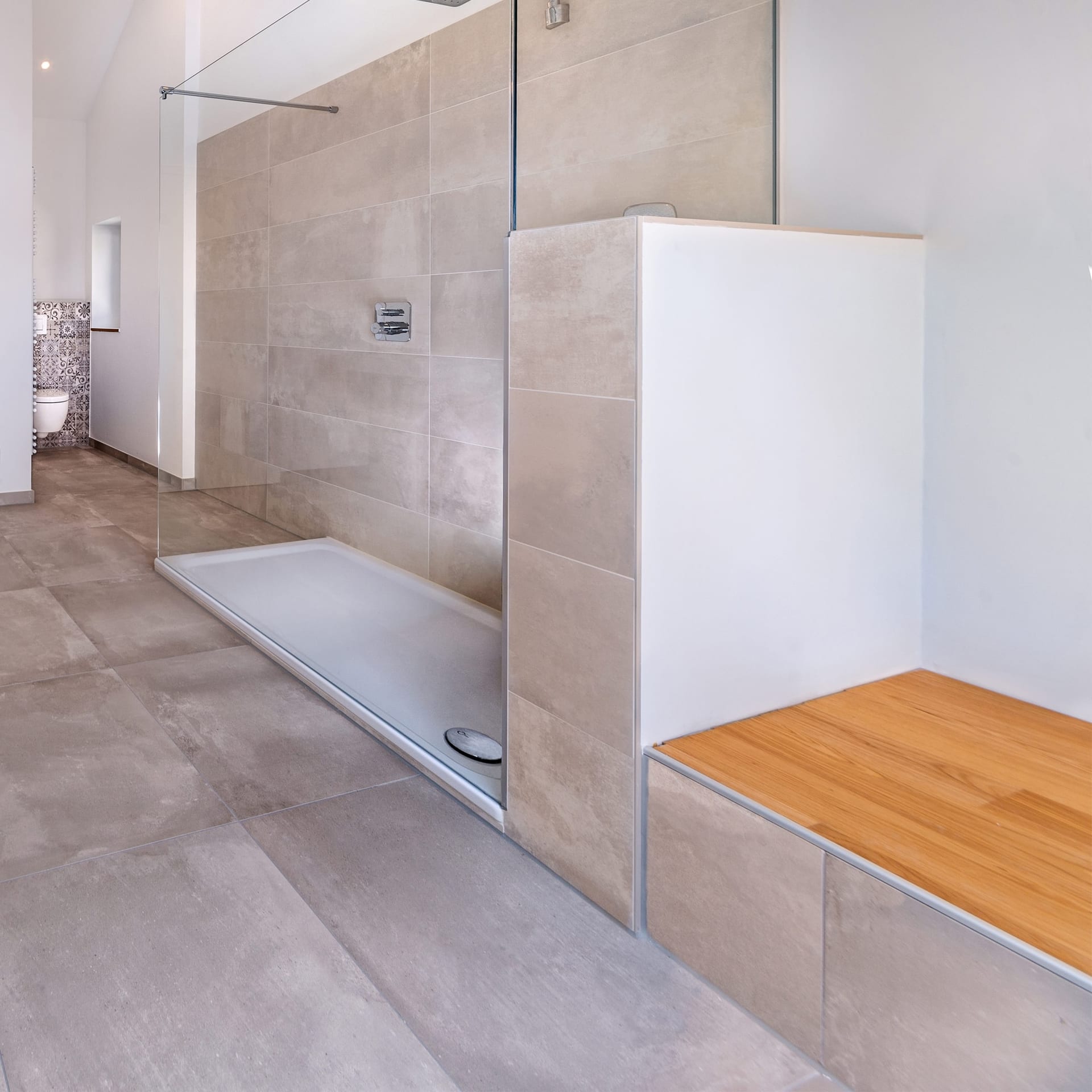 Modernes Badezimmer mit einer begehbaren Glasdusche, beigen Fliesen und einer eingebauten Holzbank