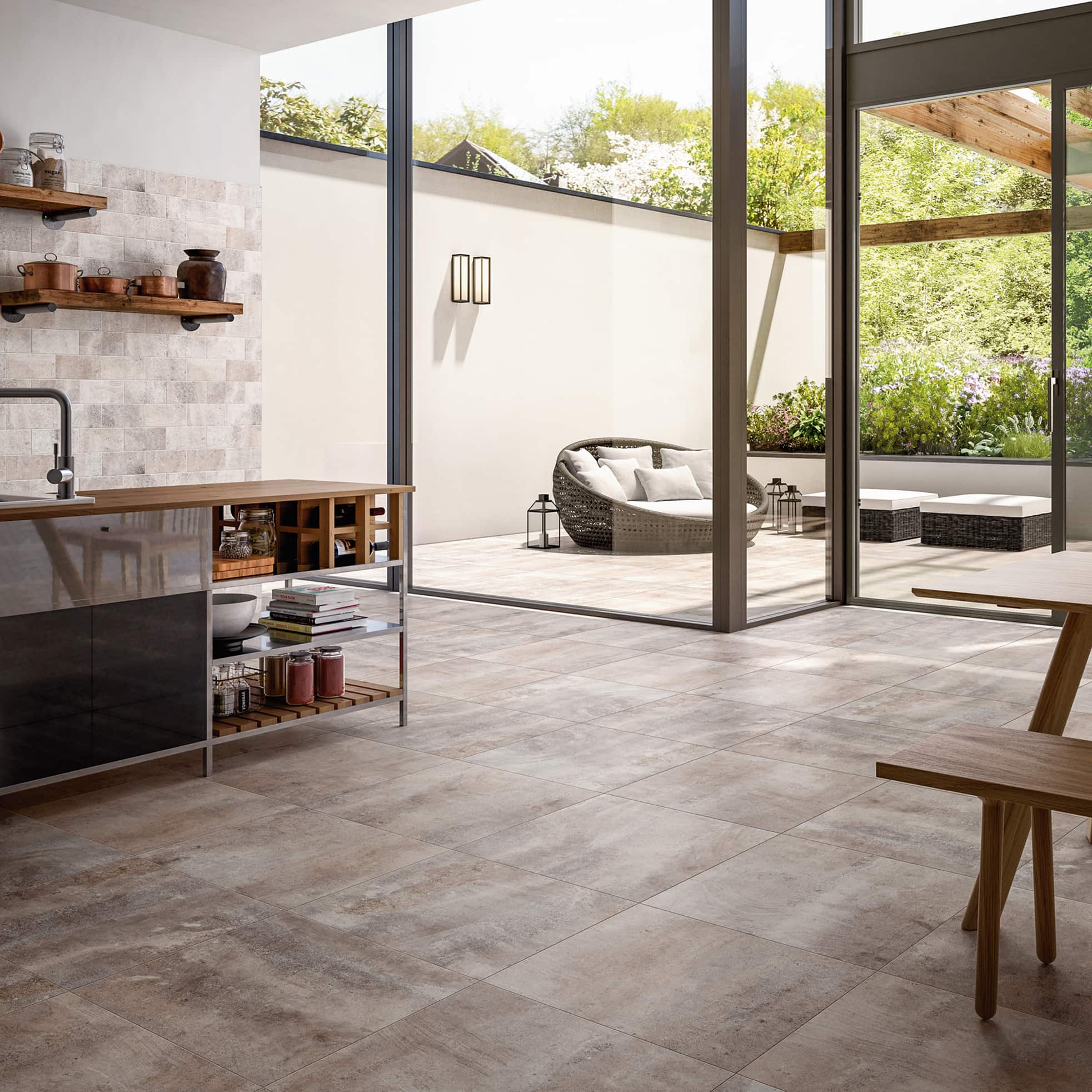 Moderne Küche mit Fliesenboden, die sich über große Glastüren zu einer Terrasse mit Sitzgelegenheiten öffnet