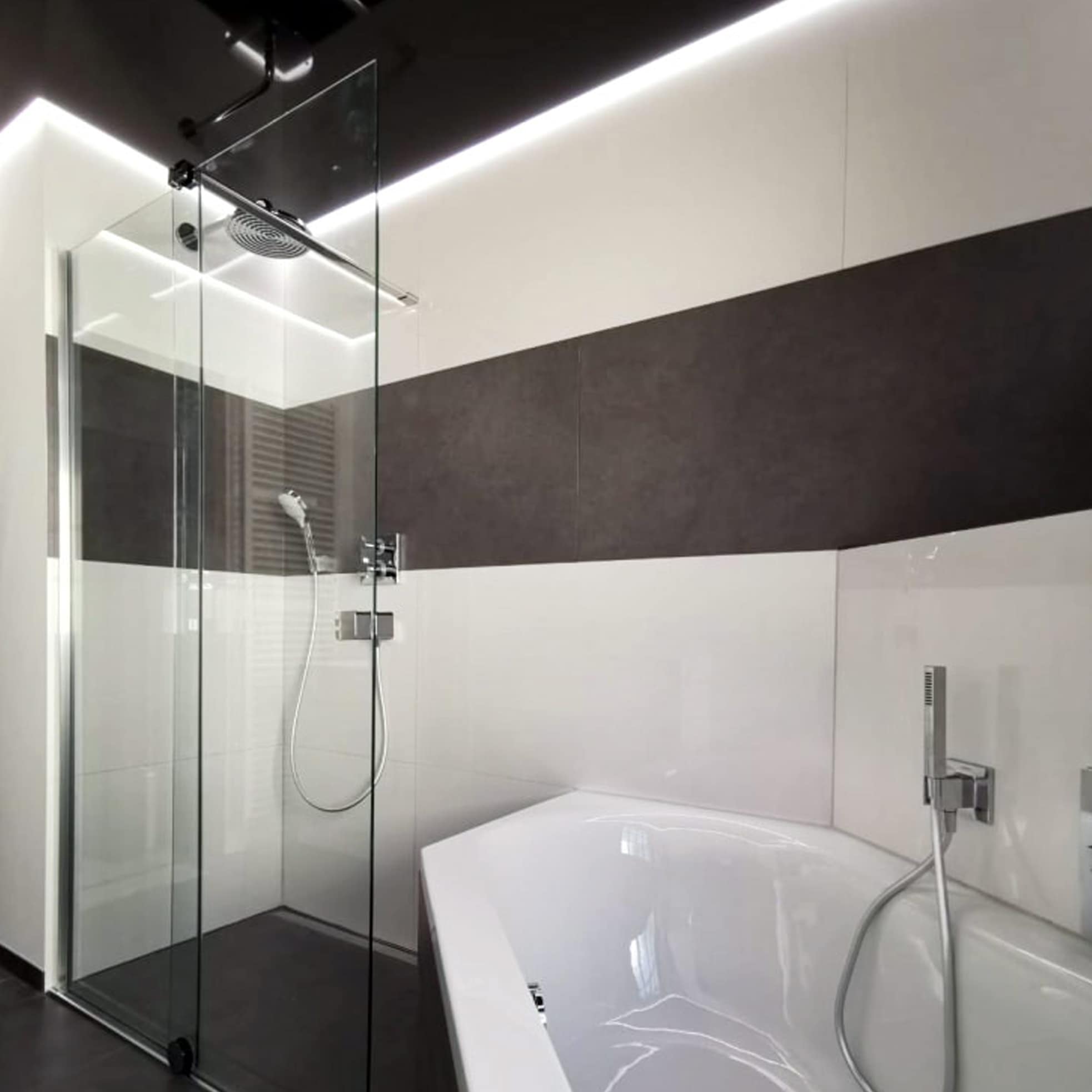 Modernes Badezimmer mit Fliesen, einer Duschkabine aus Glas, einer Regendusche und einer weißen Badewanne mit aufgesetzter Armatur